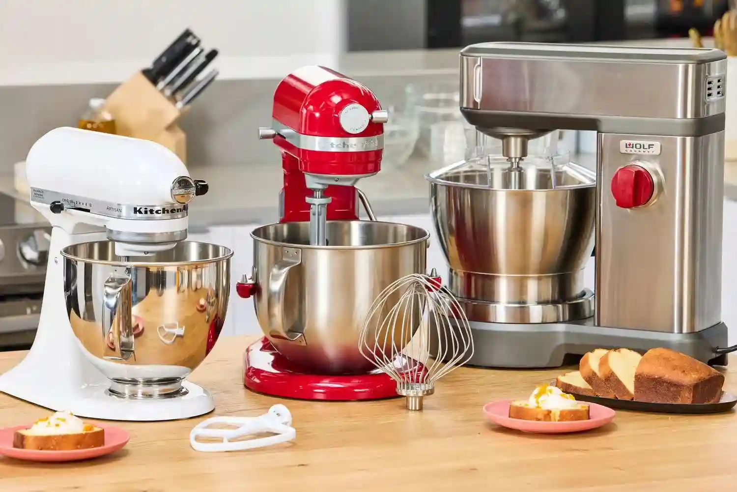 A professional stand mixer prepared for baking on a bright marble kitchen counter.